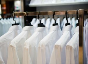 A row of white shirts hanging on black hangers.
