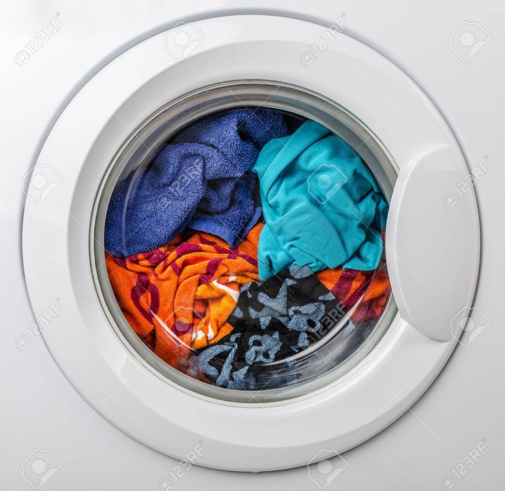 A white washer with clothes inside of it.