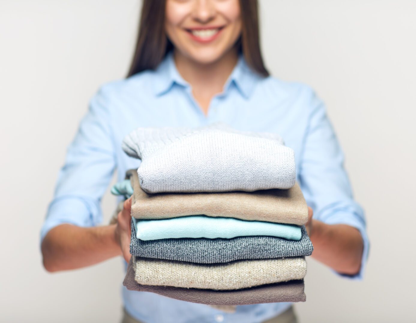 A woman holding a stack of folded clothes.